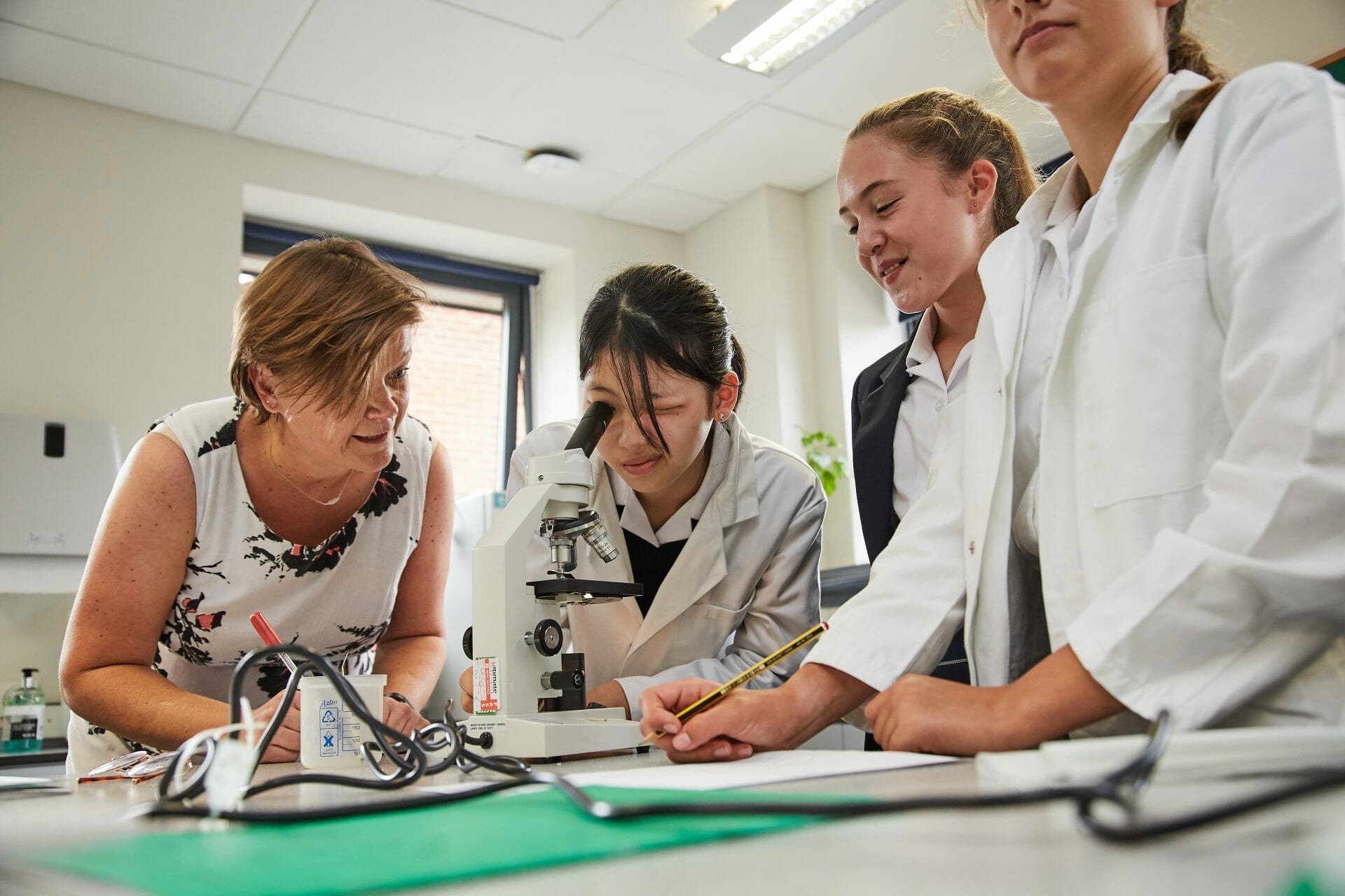 children in a science lesson using a microscope