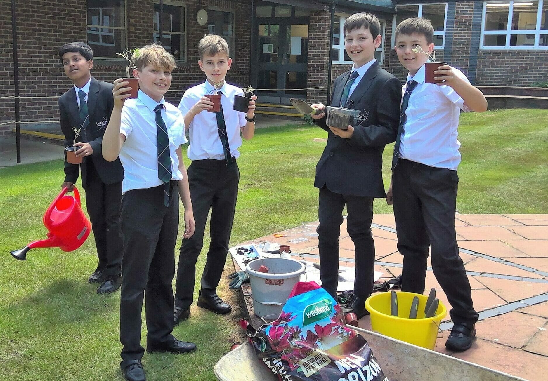 boys standing an holding plant pots