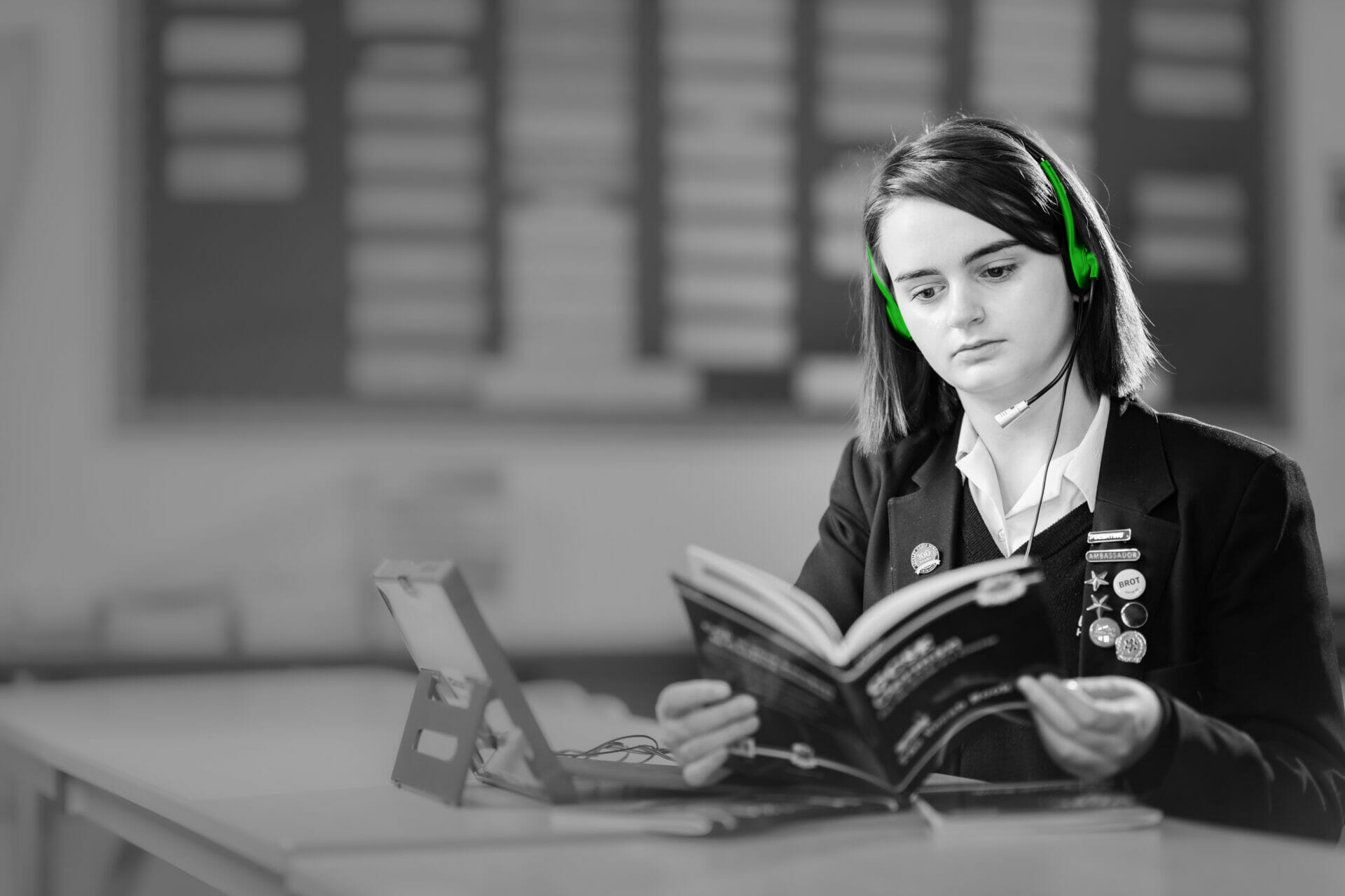 black and white photo of a girl reading whilst wearing green headphones