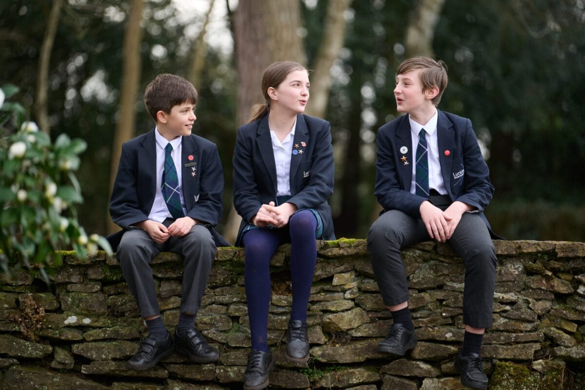 3 students sat on a rock fence wall