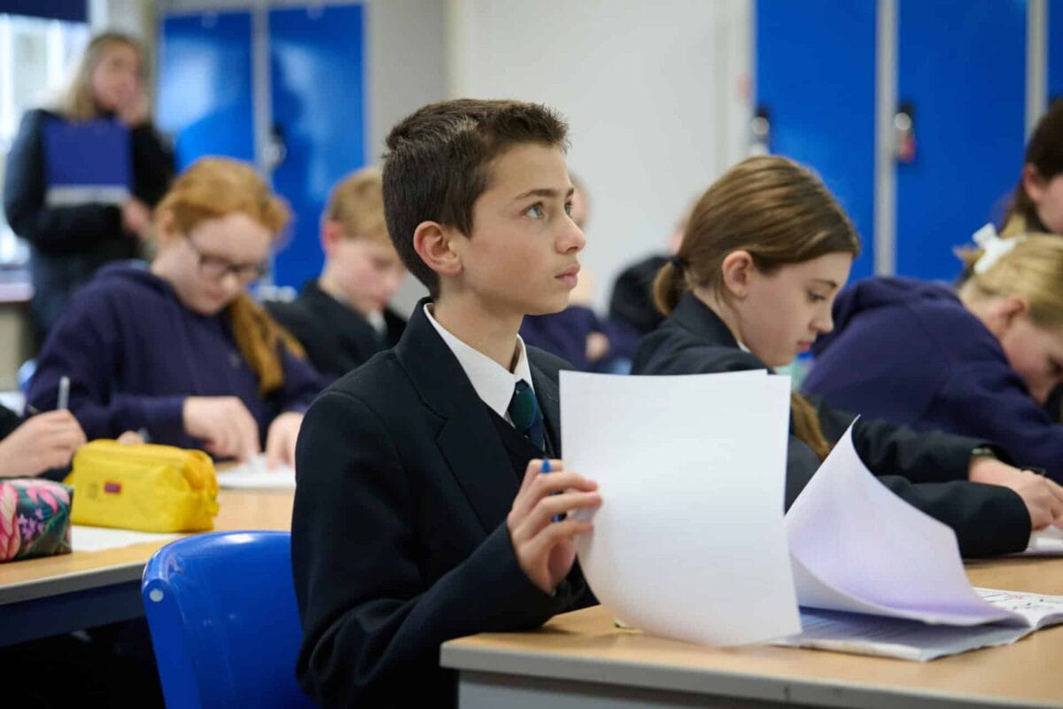 student flipping over a piece of paper on the desk