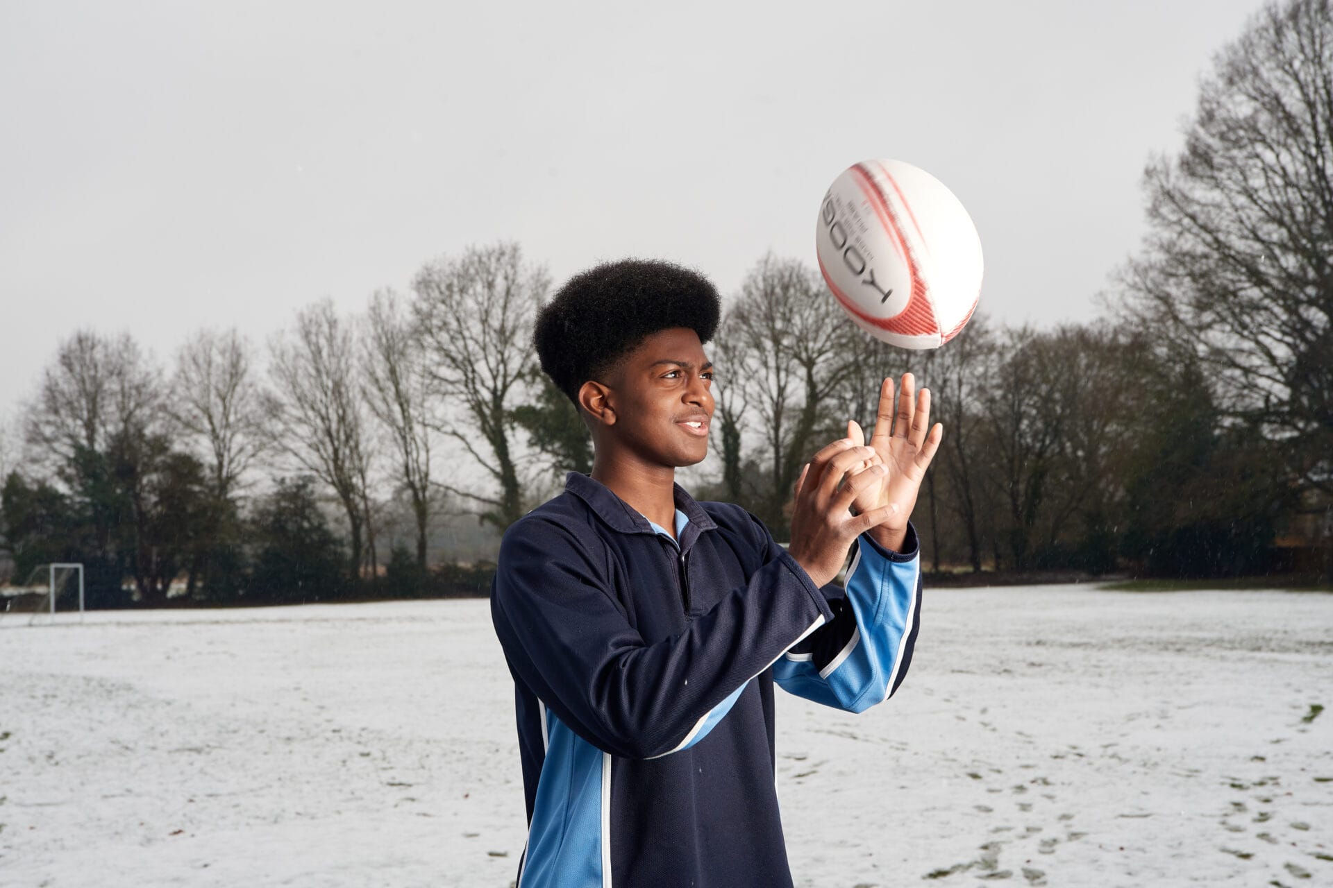 boy lifting up a rugby ball into the air